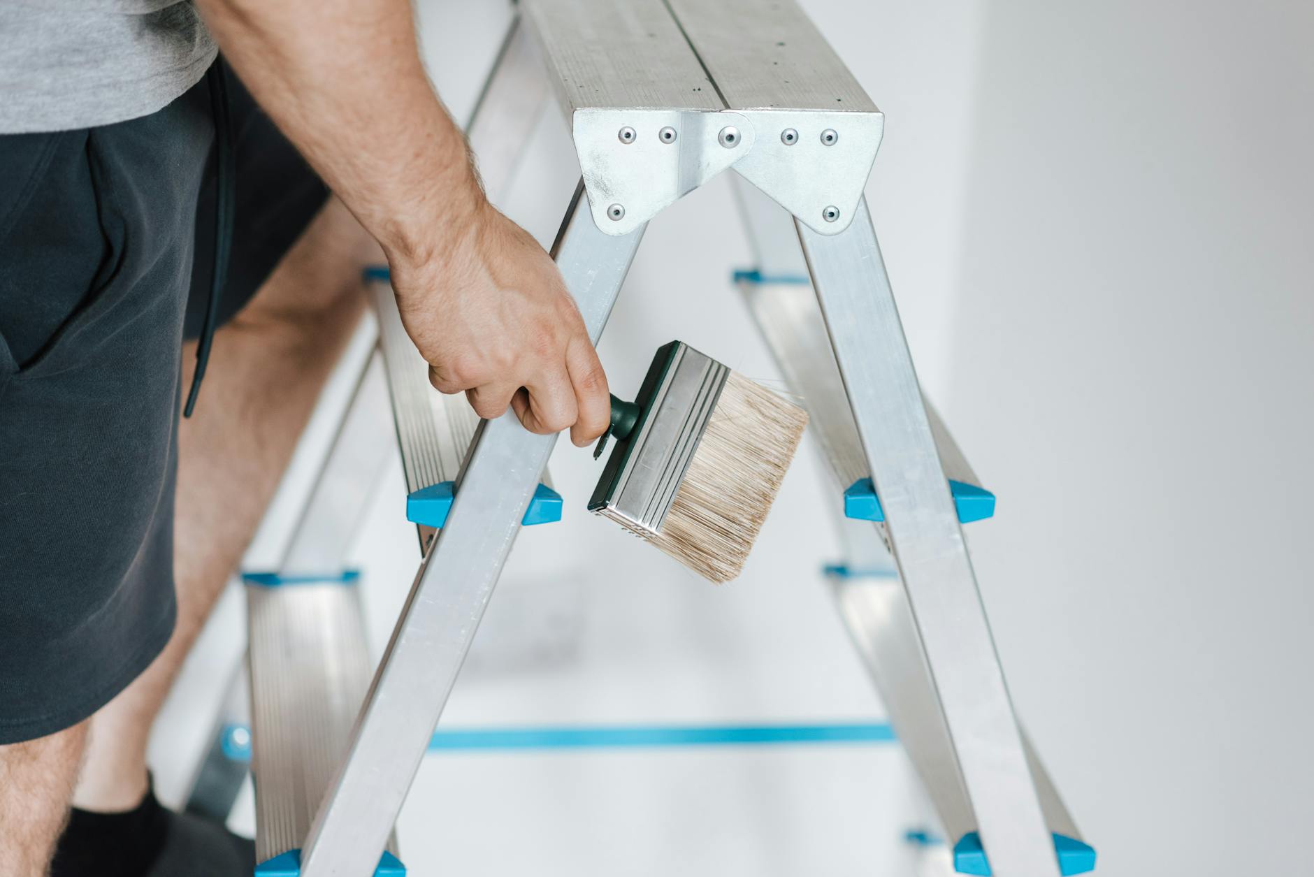 painter with brush climbing ladder during renovation work